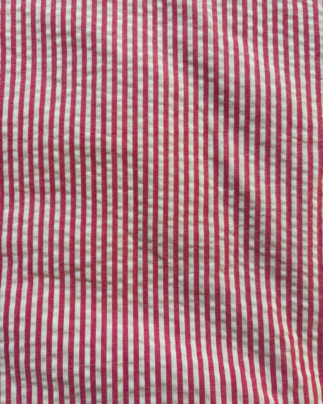 A close-up of a red and white vertically striped fabric with a visible woven texture.